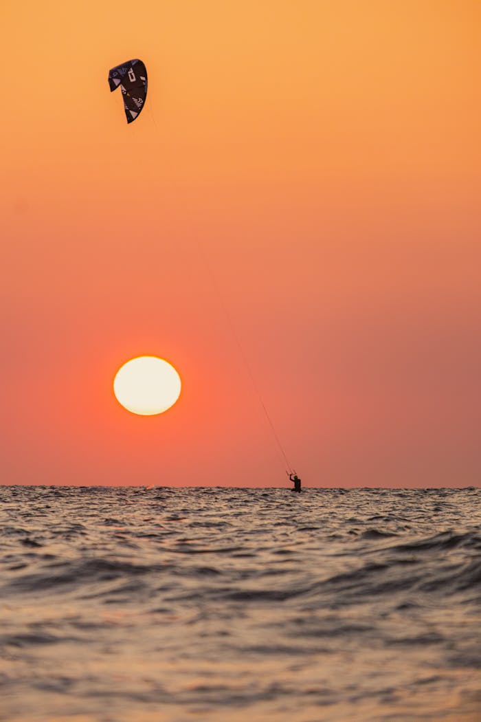 Experience thrilling kitesurfing against a vibrant sunset in Middelkerke, Belgiums beach.